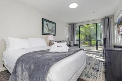 a bedroom with a bed and a large window at Greystone Lodge 113 Ski-in Out in Whistler