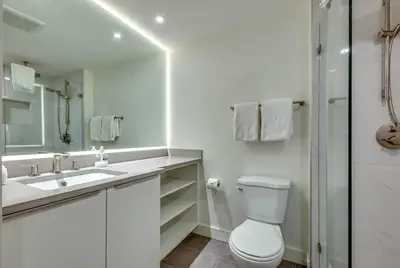 a white bathroom with a toilet and a sink at Greystone Lodge 310 Ski-in Out in Whistler