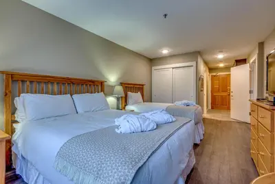 a bedroom with two beds with blue pillows on them at Greystone Lodge 310 Ski-in Out in Whistler