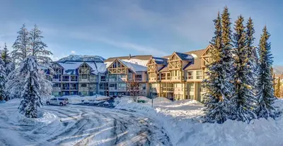 a large building covered in snow with trees in front at Greystone Lodge 310 Ski-in Out in Whistler