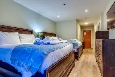 a bedroom with two beds with blue sheets at Greystone Lodge 109 Ski-in Out in Whistler