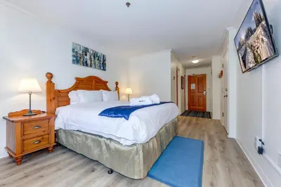 a bedroom with a large bed and a blue rug at Greystone Lodge 328 Ski-in Out in Whistler