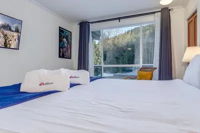 a bedroom with a large bed and a large window at Greystone Lodge 328 Ski-in Out in Whistler