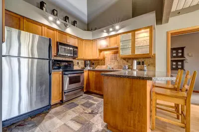 a kitchen with wooden cabinets and a stainless steel refrigerator at Greystone Lodge 311 Ski-in Out in Whistler