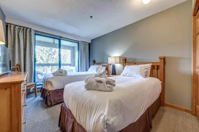 a bedroom with two beds and a window at Greystone Lodge 311 Ski-in Out in Whistler