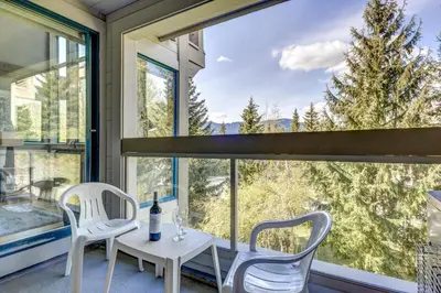 a room with a table and chairs and a large window at Greystone Lodge 311 Ski-in Out in Whistler