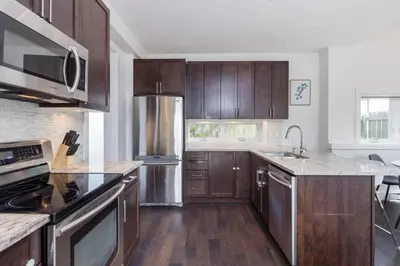 a kitchen with wooden cabinets and stainless steel appliances at West Coast Luxury Living in Vancouver