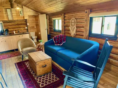 a living room with a blue couch in a cabin at Chute Lake Lodge in Naramata