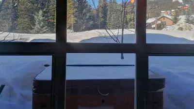 a view of a snow covered yard through a window at Crystal Forest #29 by Bear Country in Sun Peaks