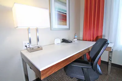 a desk in a hotel room with a lamp and a chair at Holiday Inn Express and Suites Calgary University by IHG in Calgary