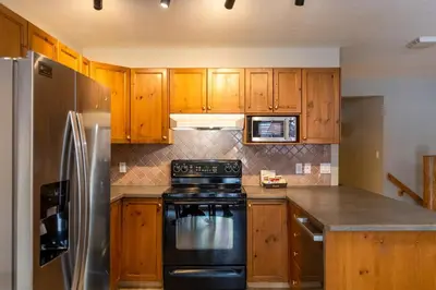 a kitchen with wooden cabinets and a black stove at Riverside Condos by Fernie Central Reservations in Fernie