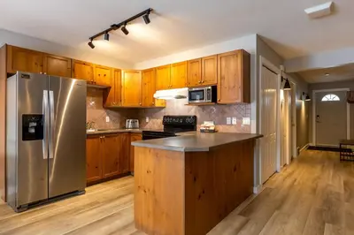 a kitchen with wooden cabinets and a stainless steel refrigerator at Riverside Condos by Fernie Central Reservations in Fernie