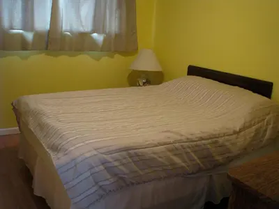 a bed in a bedroom with a lamp and a window at Fireflies Bed & Breakfast in Campbell River