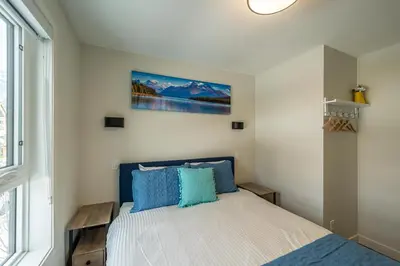 a bedroom with a bed with blue pillows at 2-in-1 Skyline MTN Retreat - Hot Tub - Pool - AC in Canmore