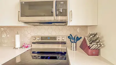 a kitchen with a stove and a microwave at 2-in-1 Skyline MTN Retreat - Hot Tub - Pool - AC in Canmore