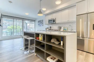 a kitchen with white cabinets and a stainless steel refrigerator at Kensington Suite 2bed & 1bath in Calgary