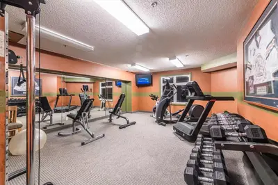 a fitness room with treadmills and exercise equipment at Windtower Lodge FullKitchen-Kingbed Suite-MntView-UGParking-Walk2DT in Canmore