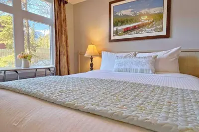 a bedroom with a large white bed with a window at Windtower Lodge Queen Bed Suite-UGParking&Walking2DT in Canmore