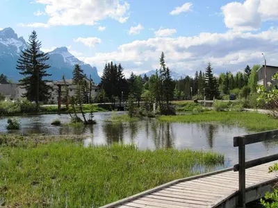 a wooden bridge over a river with mountains in the background at Apartment 406, Indigenous Artefacts in Canmore