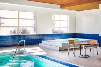 a swimming pool with a table and chairs next to a tablektop at Delta Hotels by Marriott Grande Prairie Airport in Grande Prairie