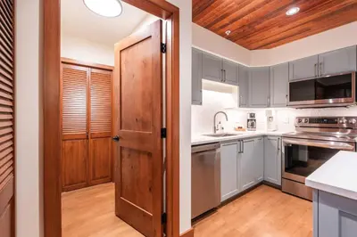 a kitchen with white cabinets and a wooden door at Snowberry by Outpost Whistler in Whistler