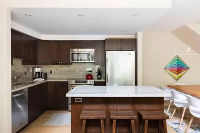 a kitchen with wooden cabinets and a kitchen island with bar stools at 3BR in Gleneagle, Ski Storage, Wood Burning Fireplace, Free Shuttle in Whistler