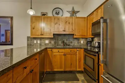 a kitchen with wooden cabinets and a stainless steel refrigerator at Settlers Crossing #08 by Bear Country in Sun Peaks