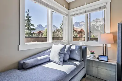 a bedroom with a couch and windows with mountains at The Versailles by Samsara Resort Top Luxury Top View 1300SQF 2BEDROOM 2BATHROM in Canmore