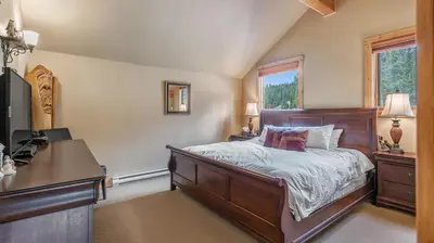 a bedroom with a bed and a desk and a window at Forest Lane Hideaway - Luxurious Family Friendly Home w Private Hot Tub in Big White