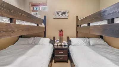 two bunk beds in a room with two beds at Forest Lane Hideaway - Luxurious Family Friendly Home w Private Hot Tub in Big White