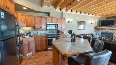 a kitchen with wooden cabinets and a table in a kitchen at Forest Lane Hideaway - Luxurious Family Friendly Home w Private Hot Tub in Big White