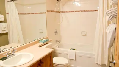 a bathroom with a sink and a tub and a toilet at Fireside Lodge #215 by Bear Country in Sun Peaks