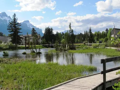 a wooden bridge over a river with mountains in the background at Apartment 407, Contemporary Decor in Canmore