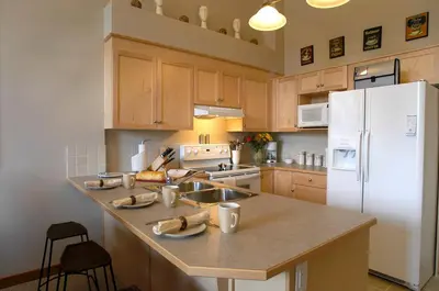 a kitchen with wooden cabinets and a white refrigerator at Apartment 411, Antique Heritage in Canmore