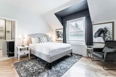 a bedroom with a bed and a chair and a window at The Inn on Officers' Garden in Calgary