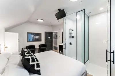 a bedroom with a white bed and a glass wall at The Inn on Officers' Garden in Calgary