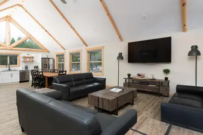 a living room with black leather furniture and a flat screen tv at Lazy Moose in Valemount
