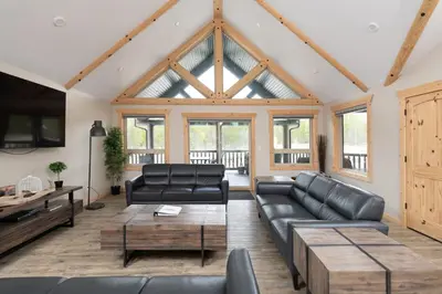 a living room with black leather furniture and wooden ceilings at Lazy Moose in Valemount