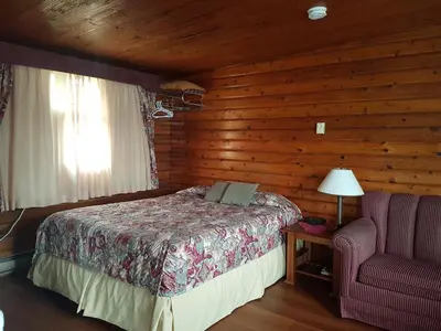 a bedroom with a bed and a chair in a cabin at Flamingo Motel in Cranbrook