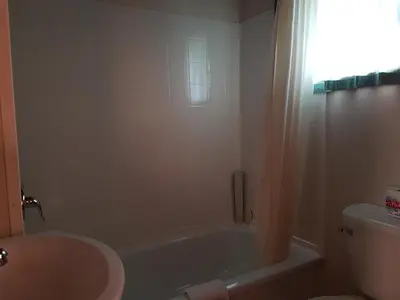 a bathroom with a tub and a toilet and a sink at Flamingo Motel in Cranbrook