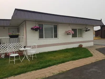 a house with two chairs and a table in front of it at Flamingo Motel in Cranbrook