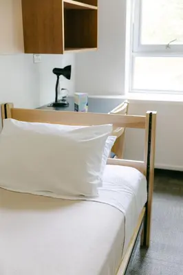 a bedroom with a bed and a desk with a lamp at Pacific Spirit Hostel in Vancouver