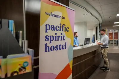 two men standing at a reception desk in an office at Pacific Spirit Hostel in Vancouver