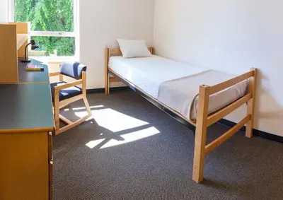 a bedroom with a bed and a desk and a chair at Pacific Spirit Hostel in Vancouver