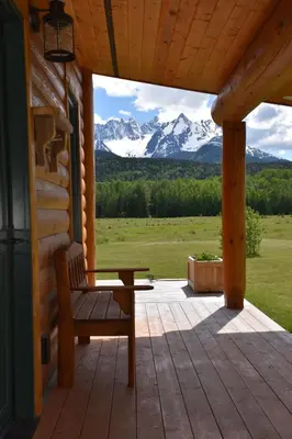 a wooden bench on a porch with a view of mountains at Seven Sisters Mountains House in Kitwanga