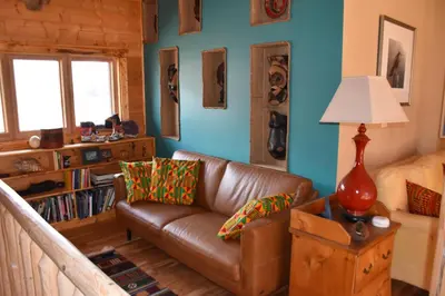 a living room with a brown leather couch and blue walls at Seven Sisters Mountains House in Kitwanga