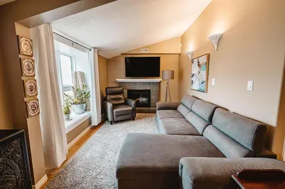 a living room with a couch and a television at The Hidden Hollow Suite - Downtown in Drumheller