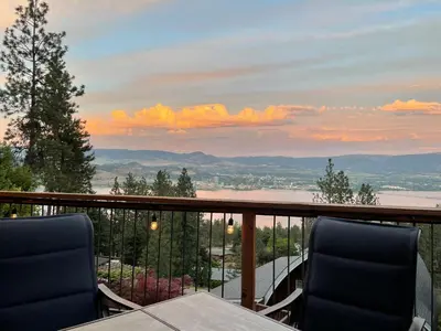 a balcony with two chairs and a view of a lake at Les Chambres Roses in West Kelowna