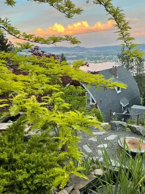 a view of a house from a garden with green plants at Les Chambres Roses in West Kelowna
