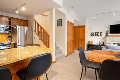 a kitchen with a counter and a table and chairs at 2BR in Symphony, Dog Friendly, Hot Tub, Private Balconies, Village Location, Parking in Whistler